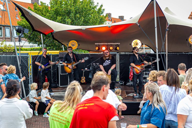 Band treedt live op onder een tent tijdens het Food & Flowers Festival in Vollenhove, terwijl bezoekers genieten van de muziek.